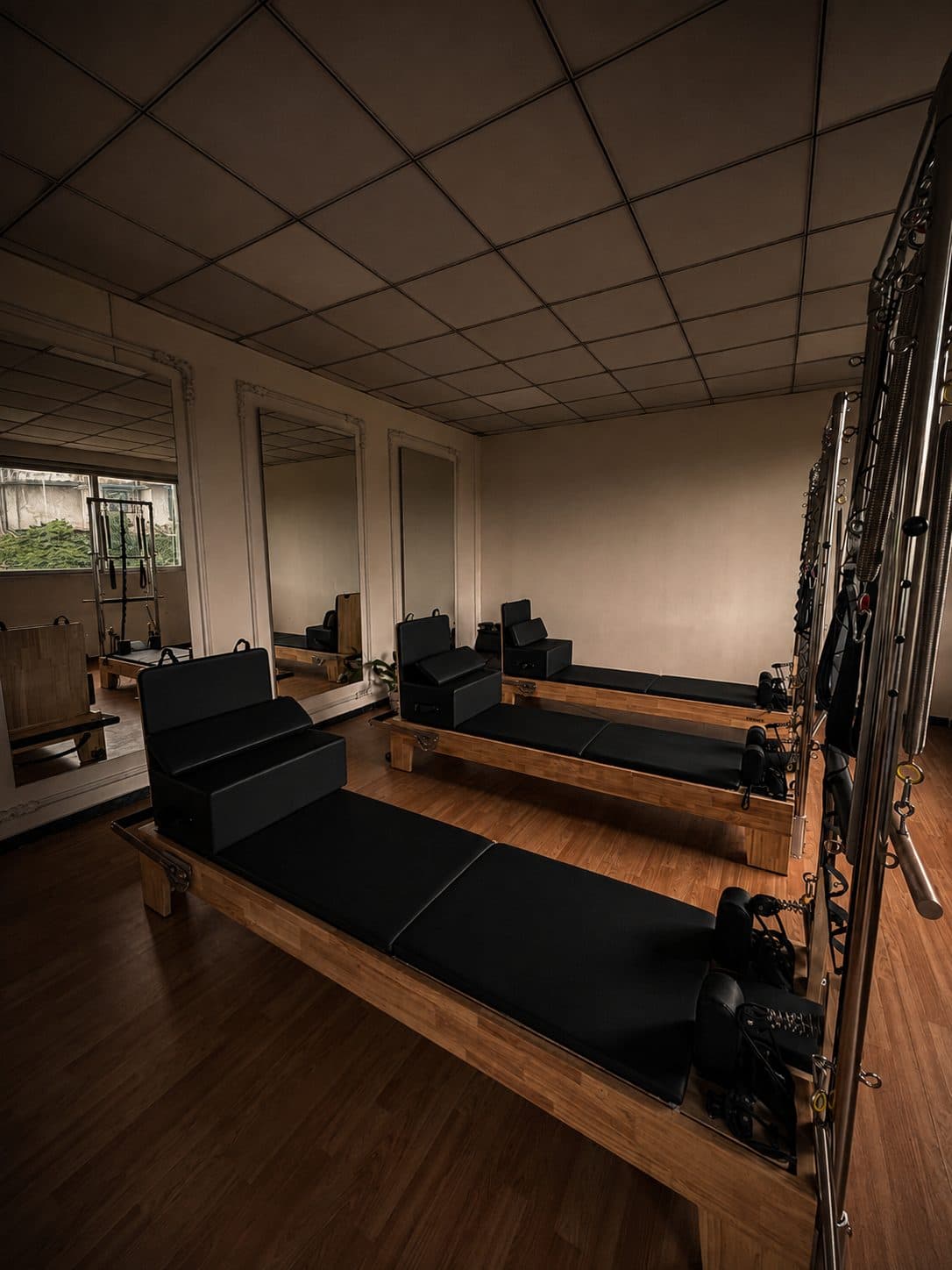 Reformer room at Sparta Life, wood frame reformers reflected in the studio mirrors